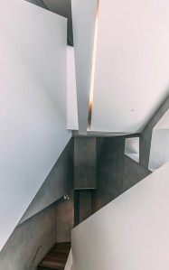Cage d'escalier blanche avec des murs brut gris anthracite